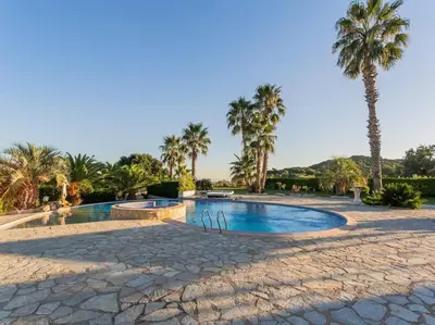 a swimming pool with palm trees in a resort at Finca Montnegre Suites and Spa in Sant Iscle de Vallalta
