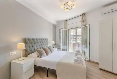 a white bedroom with a large bed and a window at Canela Homes BARCELONA BALMES in Barcelona