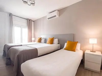 two beds in a hotel room with yellow pillows at Canela Homes BARCELONA BALMES in Barcelona