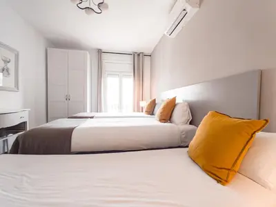 two beds in a bedroom with white and yellow pillows at Canela Homes BARCELONA BALMES in Barcelona