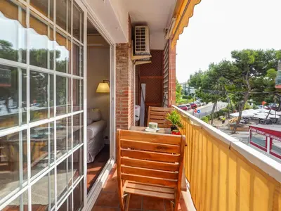 a balcony with a wooden chair and a window at The Beach Apartment by Hello Homes Sitges in Sitges