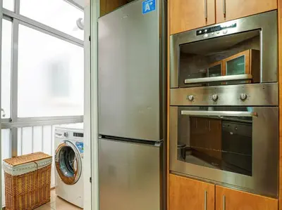 a kitchen with a stainless steel refrigerator and a washer and dryer at The Beach Apartment by Hello Homes Sitges in Sitges