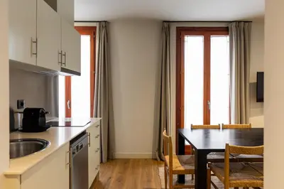 a kitchen with a sink and a table with chairs at Uma Suites Barceloneta Beach in Barcelona