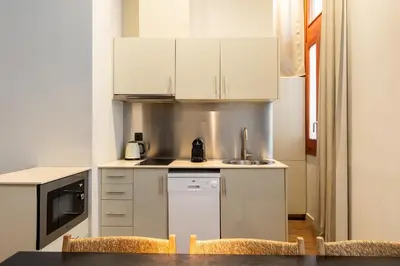 a kitchen with white cabinets and a table and chairs at Uma Suites Barceloneta Beach in Barcelona
