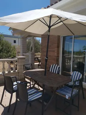 a wooden table with chairs and an umbrella on a patio at CAN TRULLEN CHALET CALAFELL in Calafell