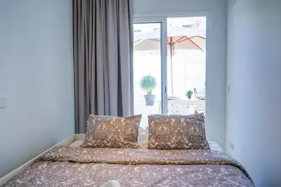 a bed with pillows in a room with a window at Camelot Apartment by Hello Homes Sitges in Sitges