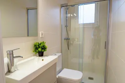 a bathroom with a shower and a toilet and a sink at Camelot Apartment by Hello Homes Sitges in Sitges