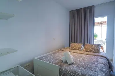 a white bedroom with a bed with a window at Camelot Apartment by Hello Homes Sitges in Sitges