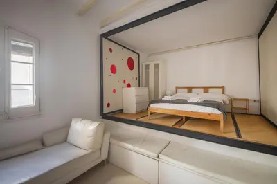 a mirror in a room with a bed and a couch at Catalunya Casas Pied-à-terre in central Barcelona 100m from beach in Barcelona