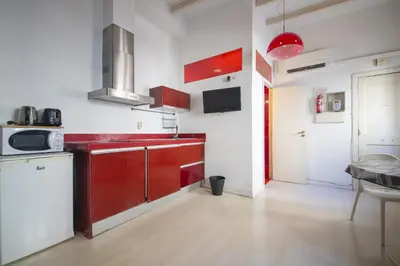 a kitchen with red cabinets and a white wall at Catalunya Casas Pied-à-terre in central Barcelona 100m from beach in Barcelona
