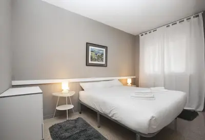 a bedroom with a white bed with two lamps at Bcn Sagrada Familia Apartments in Barcelona