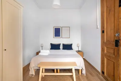 a white bedroom with a bed and a wooden table at The Collection Barcelona - Paseo St Joan classic 4BD for 10 guests in Barcelona