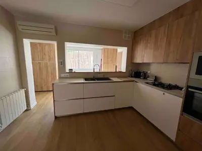 a kitchen with white counters and wooden cabinets at Casa familiar en la playa con piscina in Teià