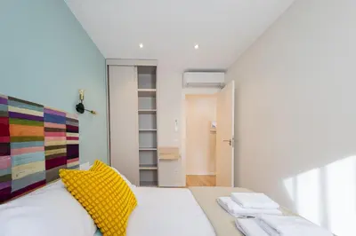 a bedroom with a white bed with a yellow pillow at MadreMia - Chic Hub Barcelona in Hospitalet de Llobregat