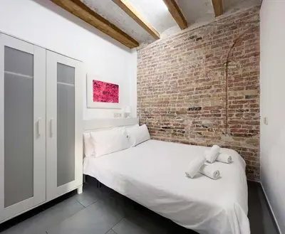 a bedroom with a white bed and a brick wall at Stay U-nique Apartment Comte Urgell II in Barcelona