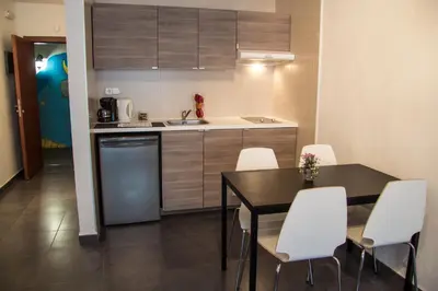 a small kitchen with a table and white chairs at Villa Sagrada in Barcelona