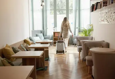 a woman with a suitcase in a room with tables at Casa Mathilda in Barcelona
