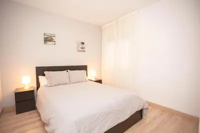 a white bedroom with a bed and two lamps at Sitges Center & Beach with Sea View in Sitges