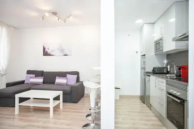 a kitchen and a living room with a couch at Sitges Center & Beach with Sea View in Sitges