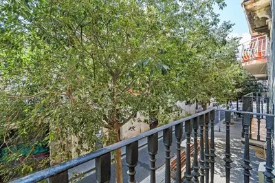 a fence next to a tree next to a building at Bright 2BR in Clot Desk Fiber Wi-Fi in Barcelona