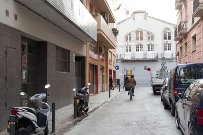 a person riding a bike down a street with parked cars at Port V Apart centrico con estilo 21 in Barcelona
