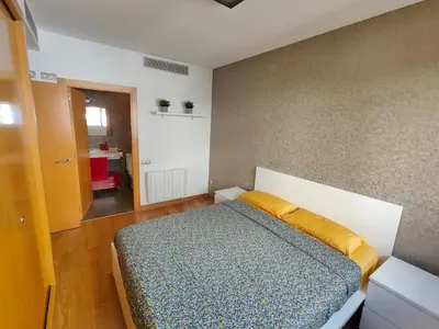 a bedroom with a bed with a yellow pillow on it at Family apartment Forum in Sant Adria de Besos