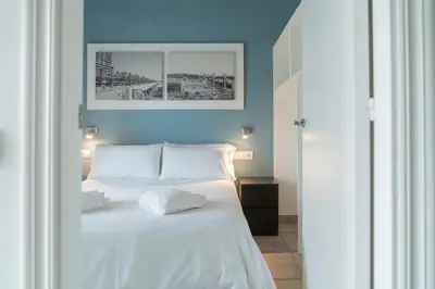a bedroom with a white bed with a blue wall at Stay U-nique Apartments Nació in Barcelona