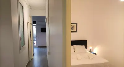a white bedroom with a bed and a hallway at Suitur apartamento floridablanca barcelona in Barcelona