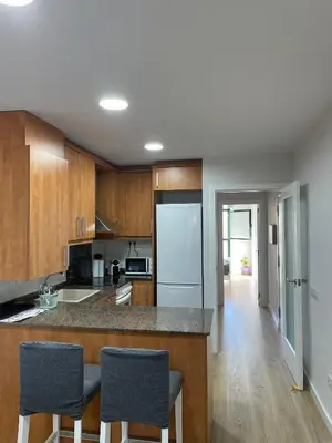 a kitchen with wooden cabinets and a white refrigerator at Acogedor apartamento Vallparadís con parking in Terrassa