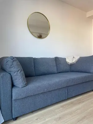 a blue couch in a living room with a mirror at Acogedor apartamento Vallparadís con parking in Terrassa
