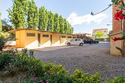 a small yellow building with cars parked in a parking lot at Apartamento Cabrera Montserrat in Cabrera de Mar