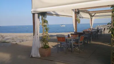 a restaurant with tables and chairs on the beach at Apartamento Cabrera Montserrat in Cabrera de Mar