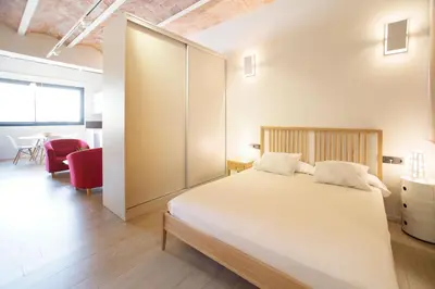 a bedroom with a large white bed and a red chair at Barcelona InLoft in Barcelona
