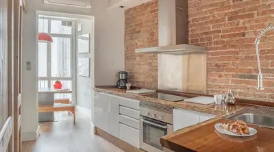 a kitchen with white cabinets and a brick wall at Stay U-nique Apartment Tamarit in Barcelona