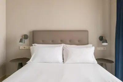 a bed with two white pillows and two lights above it at Stay U-nique Apartments Torre d'En Damians II in Barcelona
