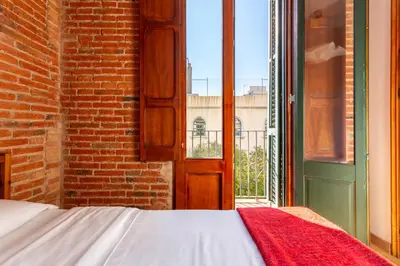 a bed in a room with a window and a brick wall at Eixample Sagrada Familia Apartments II in Barcelona