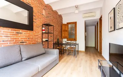 a living room with a couch and a brick wall at Eixample Sagrada Familia Apartments II in Barcelona