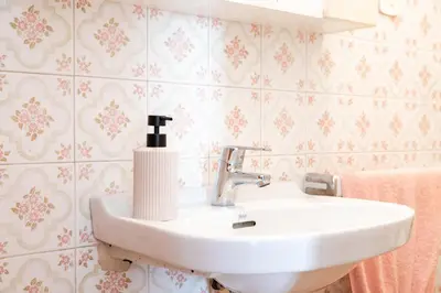a white sink in a bathroom with pink wallpaper at Secrets of Montserrat in El Bruc