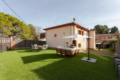 a lawn with an umbrella and a table and chairs at Secrets of Montserrat in El Bruc