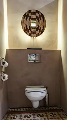a bathroom with a toilet and a circular mirror at SuiteaBCN in Barcelona