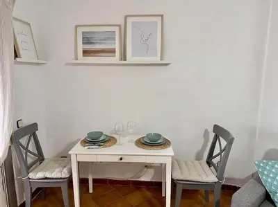 a white table and two chairs with plates and glasses at Preciosas vistas al mar en Castelldefels in Castelldefels