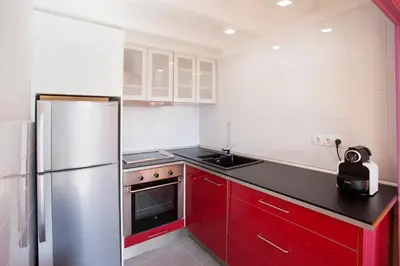 a kitchen with red cabinets and a stainless steel refrigerator at The Panoramic View Born Penthouse in Barcelona