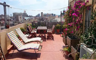 a patio with chairs and tables and flowers on a building at The Panoramic View Born Penthouse in Barcelona