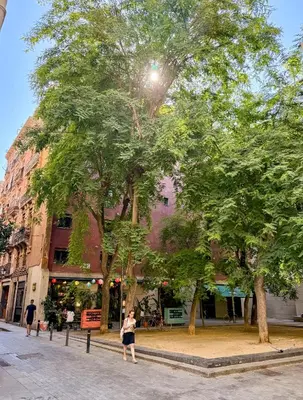 a woman walking down a street next to trees at The Luxury Open Space MACBA loft in Barcelona