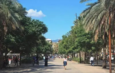 a woman walking down a street with palm trees at The Luxury Open Space MACBA loft in Barcelona