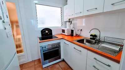 a kitchen with white cabinets and a stove and a sink at Apartamento Cabrera Burriac in Cabrera de Mar