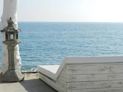 a white bench sitting next to the ocean at Apartamento Cabrera Burriac in Cabrera de Mar