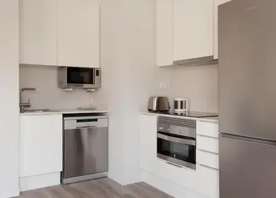 a kitchen with white cabinets and stainless steel appliances at APBCN Eixample Center in Barcelona