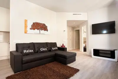 a living room with a black leather couch and a tv at APBCN Eixample Center in Barcelona