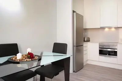 a kitchen with a table with two chairs and a refrigerator at APBCN Eixample Center in Barcelona